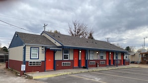 A motel with numbered rooms, a resident parking sign, and a parking lot. - Cabins on Main Longmont (Longmont)