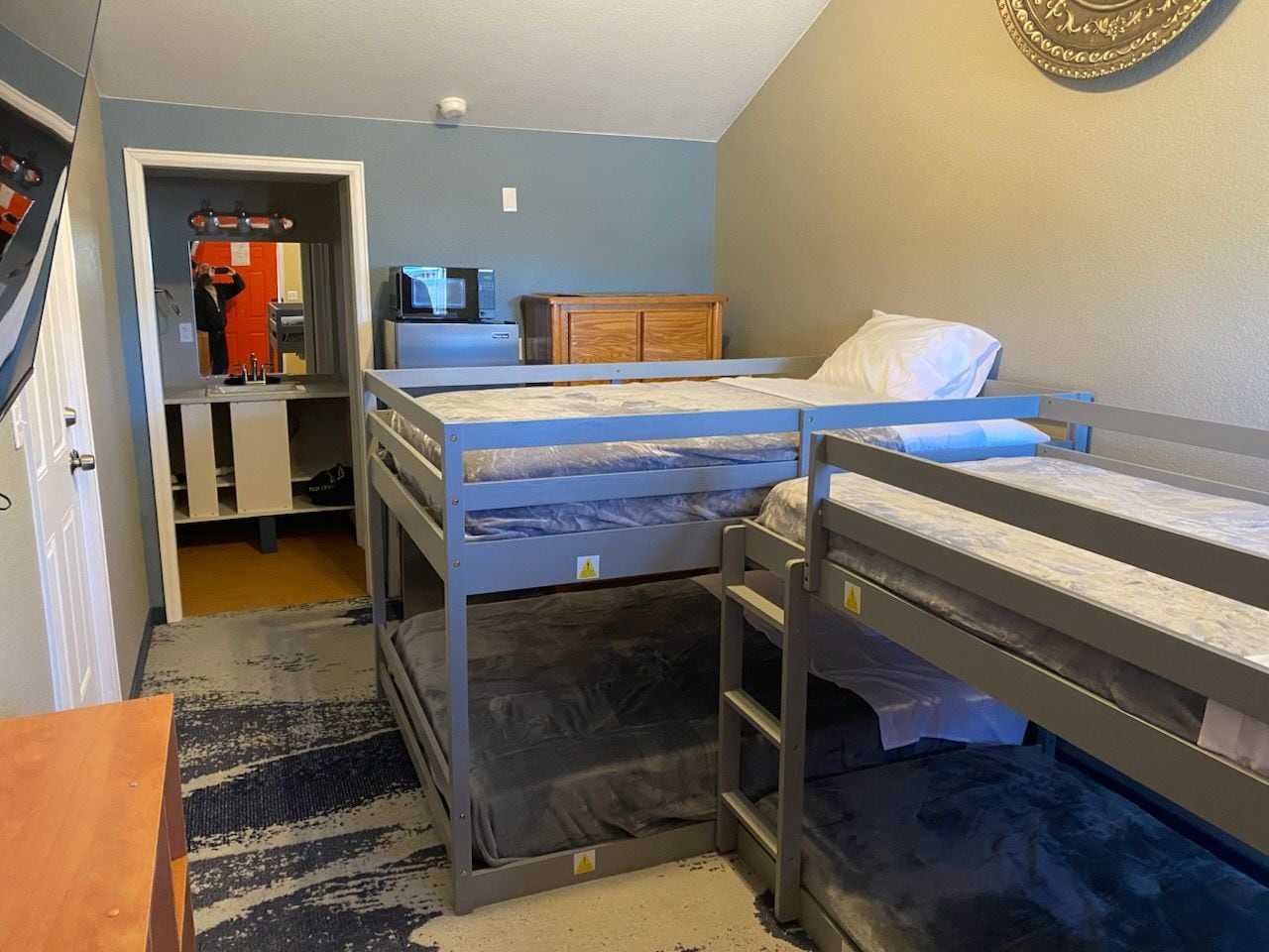 A small, compact room with bunk beds, a desk with a computer, and a microwave.