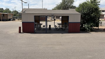 Une petite structure extérieure dotée d’une table et de bancs, probablement un espace de repos ou un kiosque.