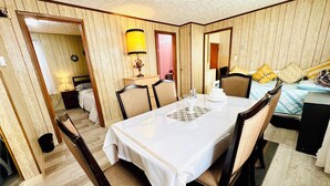 Uma área de jantar com mesa posta para seis pessoas, rodeada por cadeiras de madeira com assentos acolchoados.