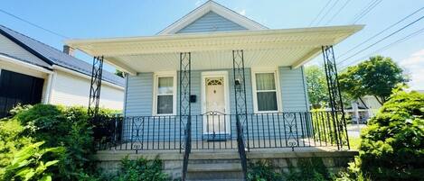 A two-story house with a porch, a front door, and a small front yard.