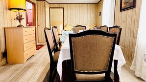 Uma sala de jantar com paredes de madeira, um armário de madeira, uma mesa com cadeiras e um abajur.