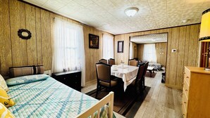 Quarto com cama, mesa de jantar e área de estar separada.