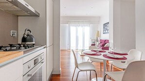 A modern kitchen with a gas stove, a kettle, and a dining area with a table set for four. - 15 Minutes Walk From Vatican Museums (Roma)