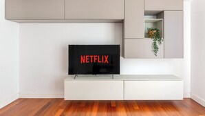 A modern living room with a flat-screen TV mounted on a white entertainment unit, a grey cabinet above, and a small plant on the right. - 15 Minutes Walk From Vatican Museums (Roma)