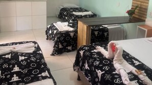 A hotel room with two beds, a small desk, and a window with blinds. - Pousada Oasis Beach Club (Canavieiras)