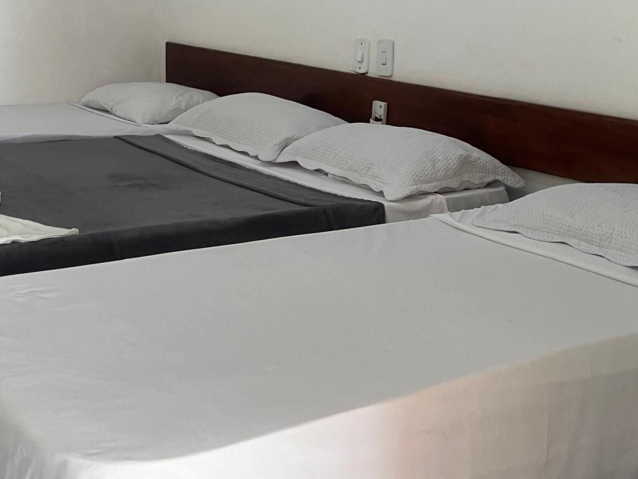Una habitación de hotel con dos camas individuales, cada una con un colchón gris y almohadas blancas.