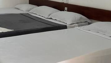 Una habitación de hotel con dos camas individuales, cada una con un colchón gris y almohadas blancas.