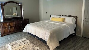 Ein Schlafzimmer mit Bett, Kommode, Spiegel und Klimaanlage.