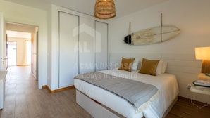 Ein Schlafzimmer mit einem Bett, einer Hängelampe und einem Surfbrett an der Wand.