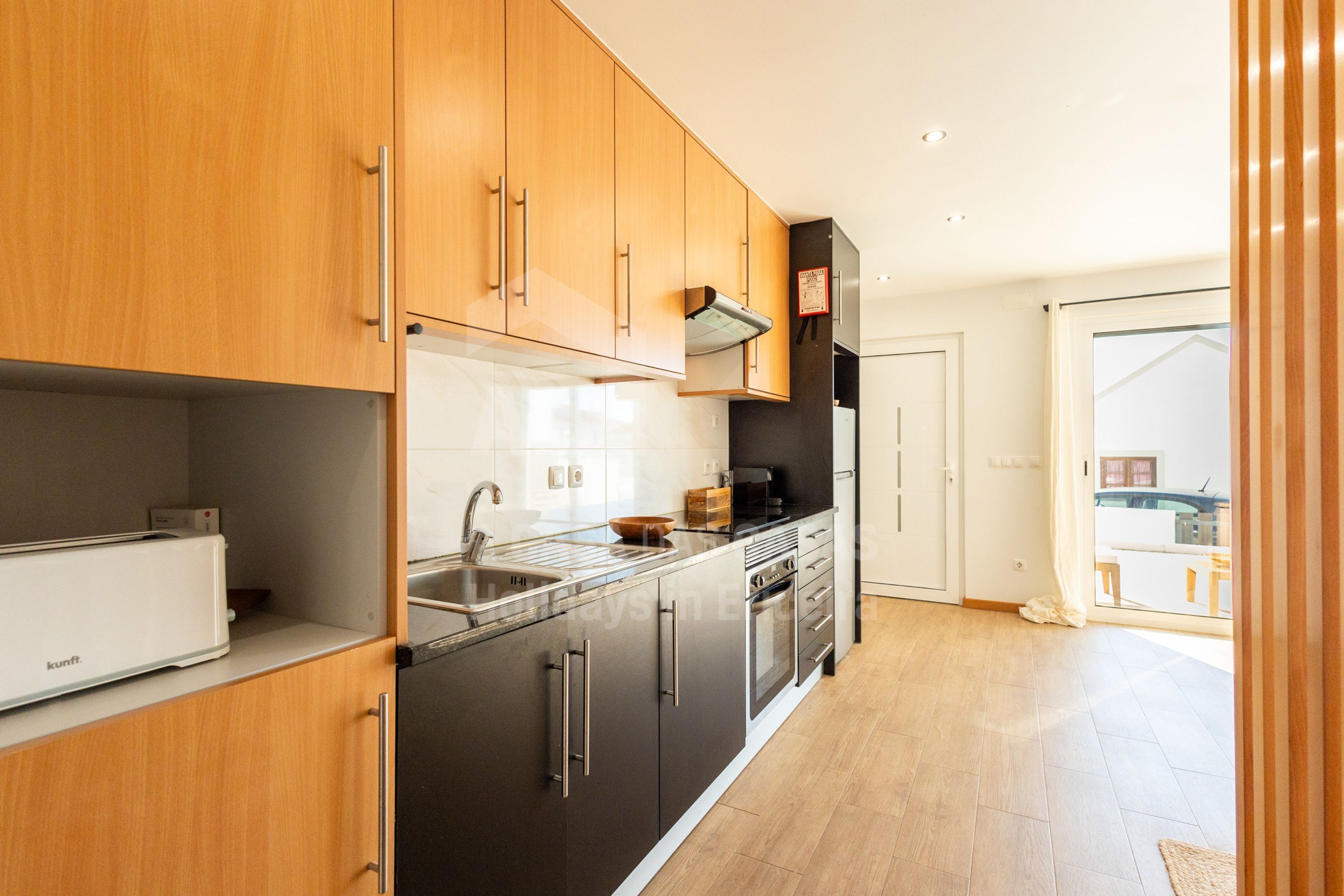 A modern kitchen with wooden cabinets, stainless steel appliances, and a large window.