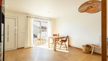 A spacious room with a wooden dining table, chairs, and a woven pendant light.