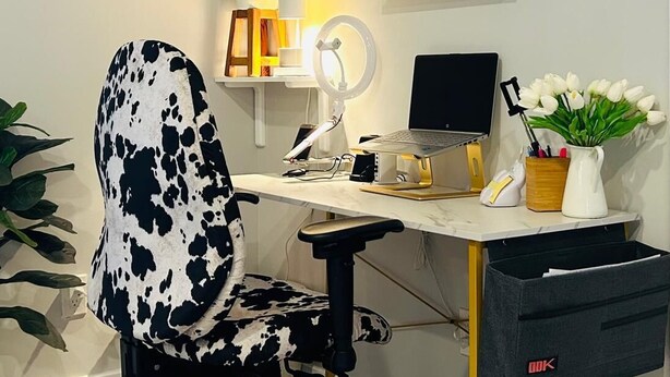 Un espacio de trabajo en casa con escritorio, silla, computadora y varios objetos decorativos.