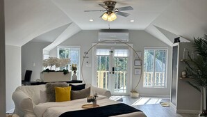 Un dormitorio amplio con una cama grande, un ventilador de techo y vistas al exterior a través de un ventanal.