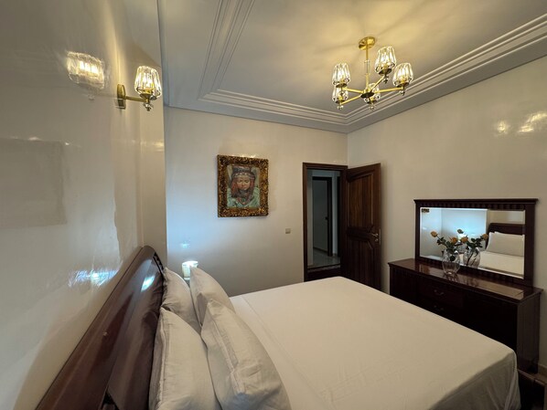 A bedroom with a bed, a nightstand, a mirror, and a chandelier.
