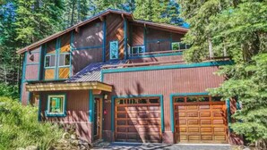 A two-story wooden house with a garage, surrounded by trees. - Palisades-Alpine Home w/ Hot Tub (Alpine Meadows)