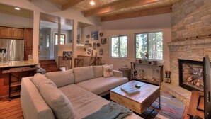 A cozy living room with a large sectional sofa, a wooden coffee table, and a stone fireplace. - Palisades-Alpine Home w/ Hot Tub (Alpine Meadows)