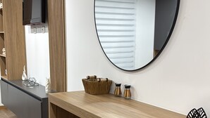 Ett modernt kök med en bänkskiva i trä, två barstolar, en stor spegel och en tv som är monterad på väggen.