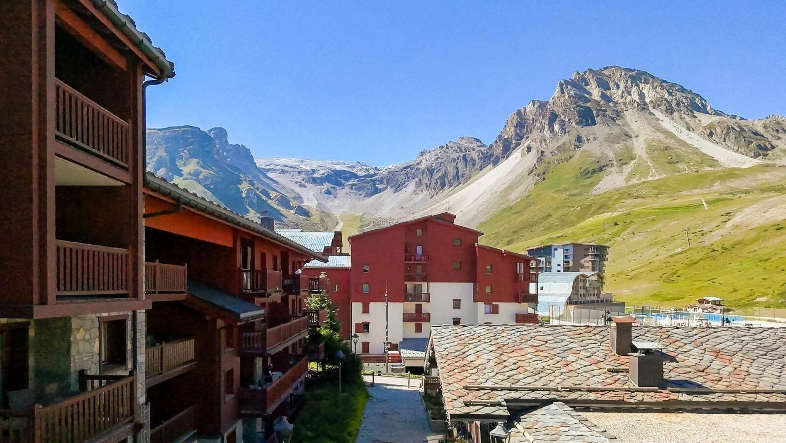 A mountain village with traditional buildings, a clear sky, and a prominent mountain in the background.