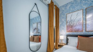 A hotel room with a bed, a large mirror, a nightstand with a lamp, and two framed pictures on the wall. - OTR by TQL+Smart TVs+King Bed+Wifi+Sleeps 3+1st Fl (Cincinnati)