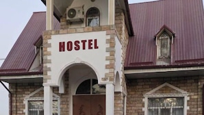 A hostel with a prominent "HOSTEL" sign, a central entrance with an arch, and a staircase leading to the entrance. - DDS Hostel (Tashkent)