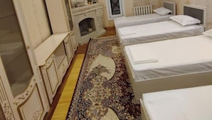 A hotel room with two beds, a vanity with a mirror, a dresser, and a patterned rug. - DDS Hostel (Tashkent)