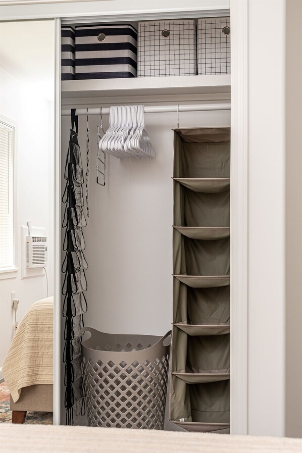 Een kast met opbergmanden, opgehangen tassen, planken en een wasmand.