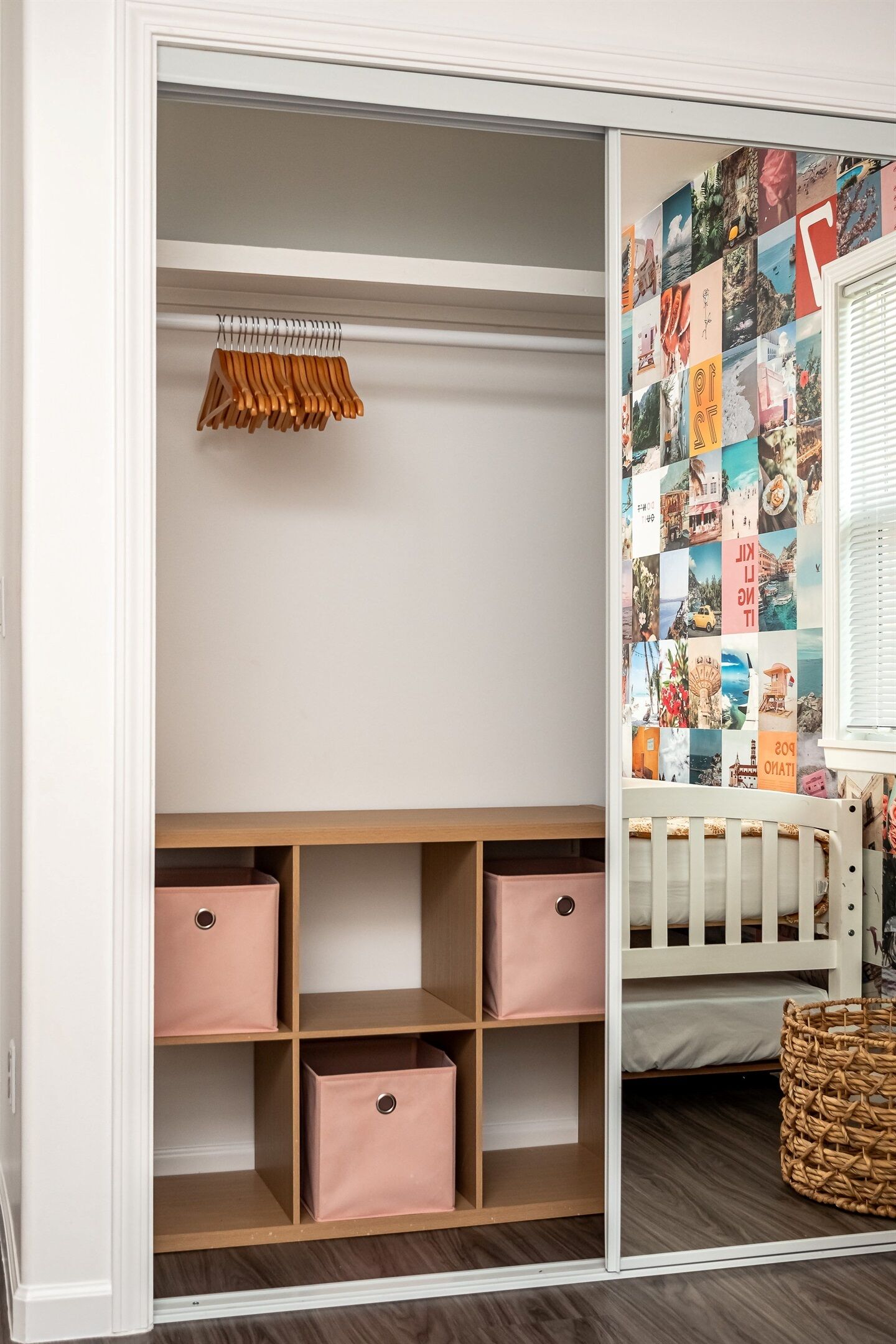 A walk-in closet with open shelves, a hanging rack, and a crib with a patterned wall.