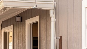 A wooden exterior wall with a door, a window, and a hose connected to a faucet.