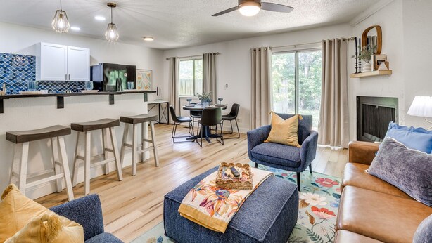 A modern living room with a sofa, armchairs, a coffee table, and a dining area with a table and chairs. There is a ceiling fan, pendant lights, and a fireplace. - Tulsa Expo Modern Chic Stay - 1.5 mi to expo (Tulsa)