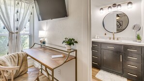 A modern bathroom with a large mirror, vanity, and a flat-screen TV mounted on the wall. - Tulsa Expo Modern Chic Stay - 1.5 mi to expo (Tulsa)