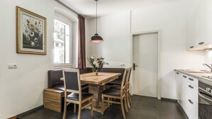 Une cuisine moderne avec un coin repas, comprenant une table en bois, des chaises, un vase avec des fleurs et un luminaire suspendu.