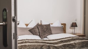Un lit avec une couverture à rayures, des oreillers blancs et un plaid marron.