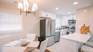 A modern kitchen with white cabinetry, stainless steel appliances, and a central island with seating. - The Central Nest-3bd/1bth -2.5miles from Casino (Danville)