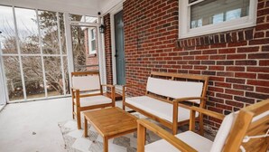 A covered porch with a brick wall, a wooden bench, and a table. - The Central Nest-3bd/1bth -2.5miles from Casino (Danville)