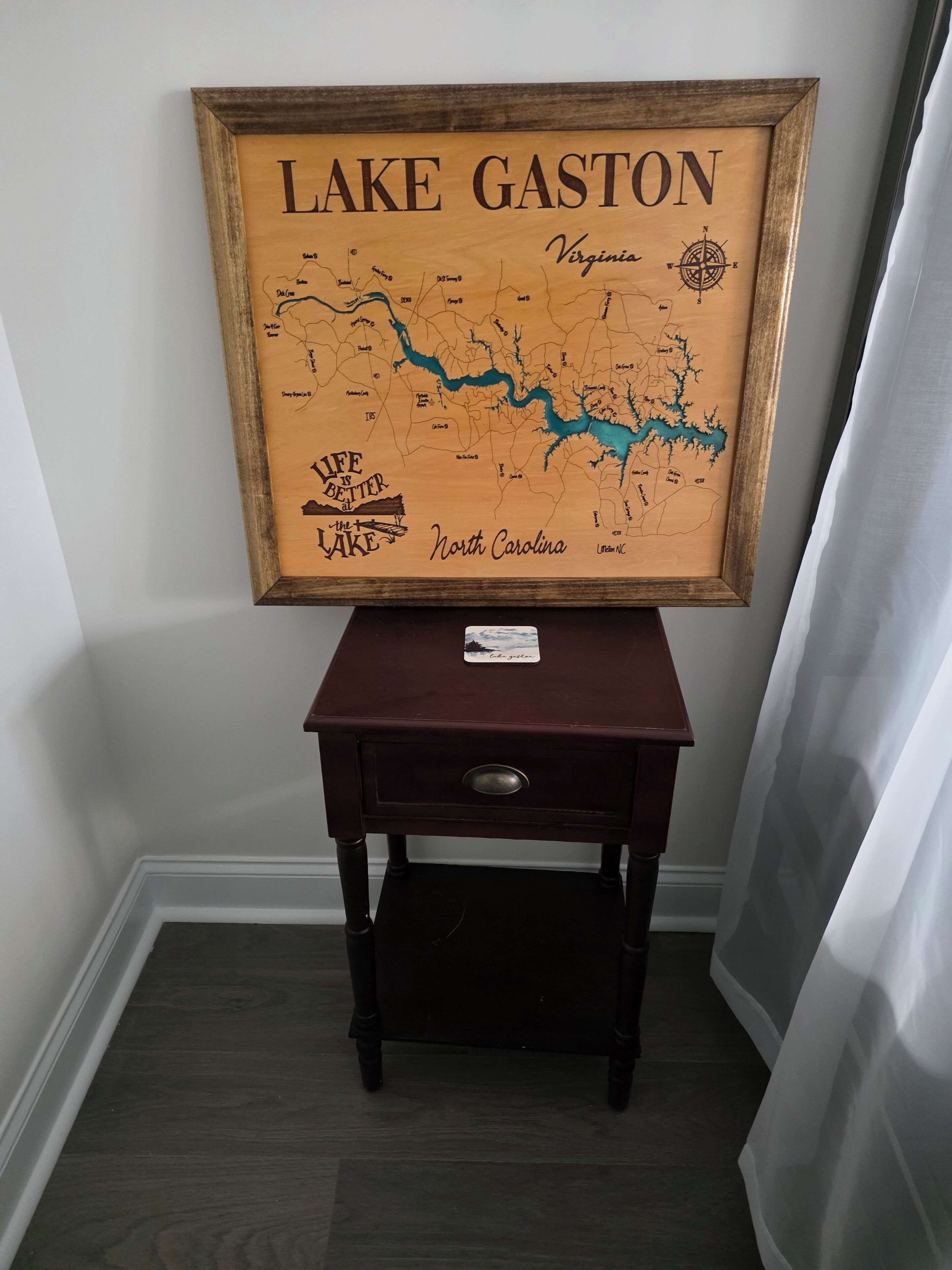 A framed map of Lake Gaston and North Carolina on a wooden table.