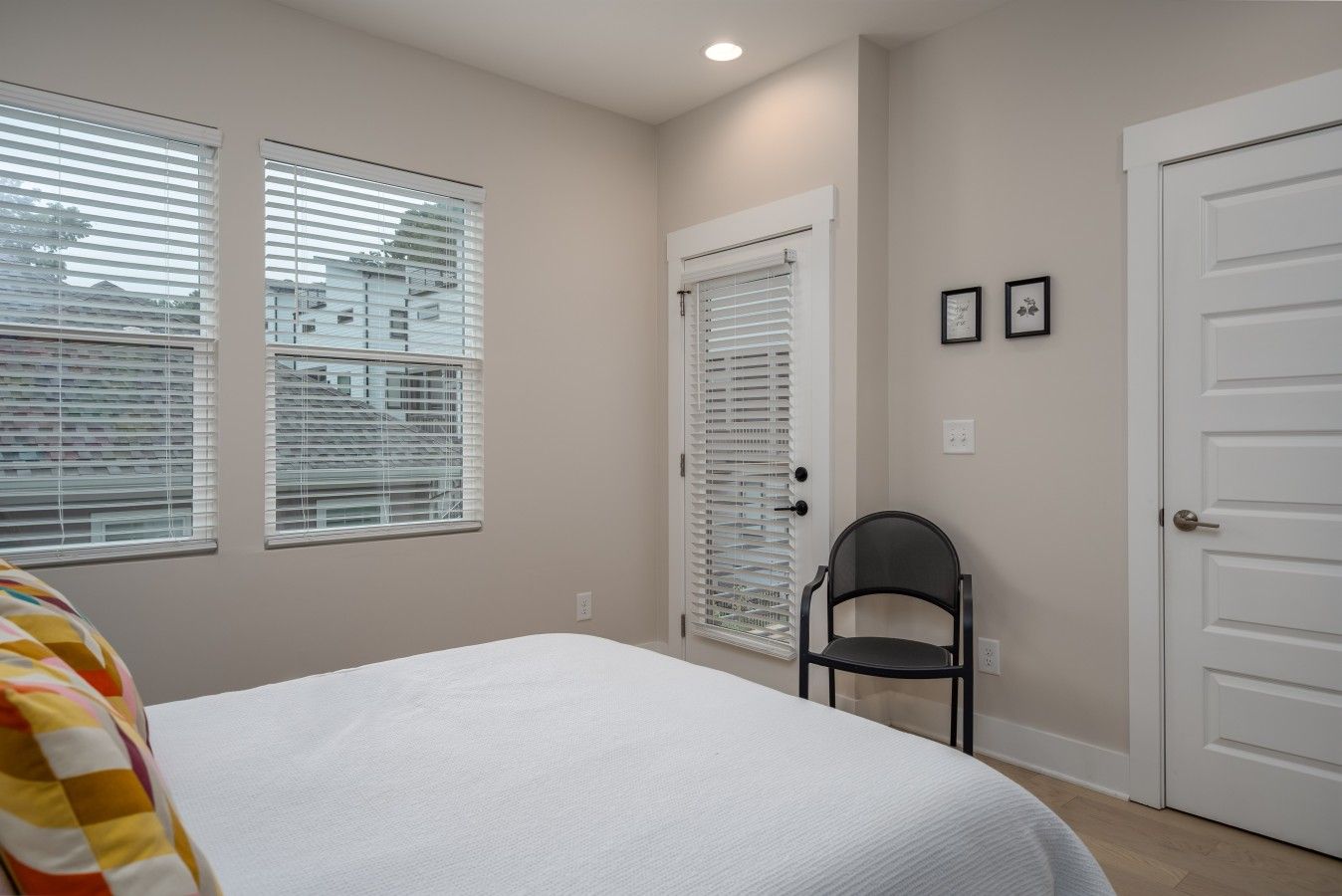 A bedroom with a bed, a chair, and two doors.