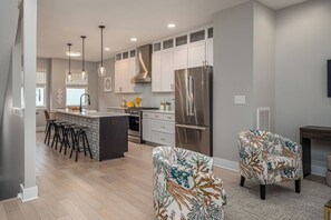 A modern kitchen with white cabinetry, stainless steel appliances, and a central island with bar stools.