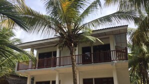 A two-story building with a balcony, surrounded by palm trees. - Sun Ray Beach Villa (Kahandamodara)