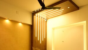 Un espace d’accueil moderne, doté d’un comptoir de réception en bois, d’un ventilateur de plafond et d’un panneau lumineux fixé au mur.