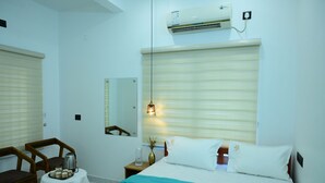 Une chambre d’hôtel comprenant un lit, une table avec un plateau de collations, une chaise, une table de chevet, un miroir et un appareil de climatisation.