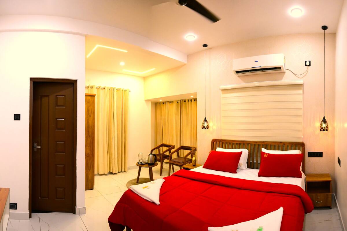 A hotel room with a bed, a desk, a chair, and an air conditioning unit.