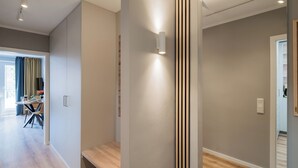 A modern interior with a wooden bench, a wall-mounted light, and a view into another room. - Fewo7Home New opening apartment at the university (Oldenburg)