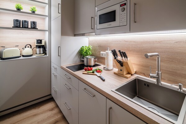 A modern kitchen with a stainless steel sink, a microwave, a coffee maker, and a toaster.