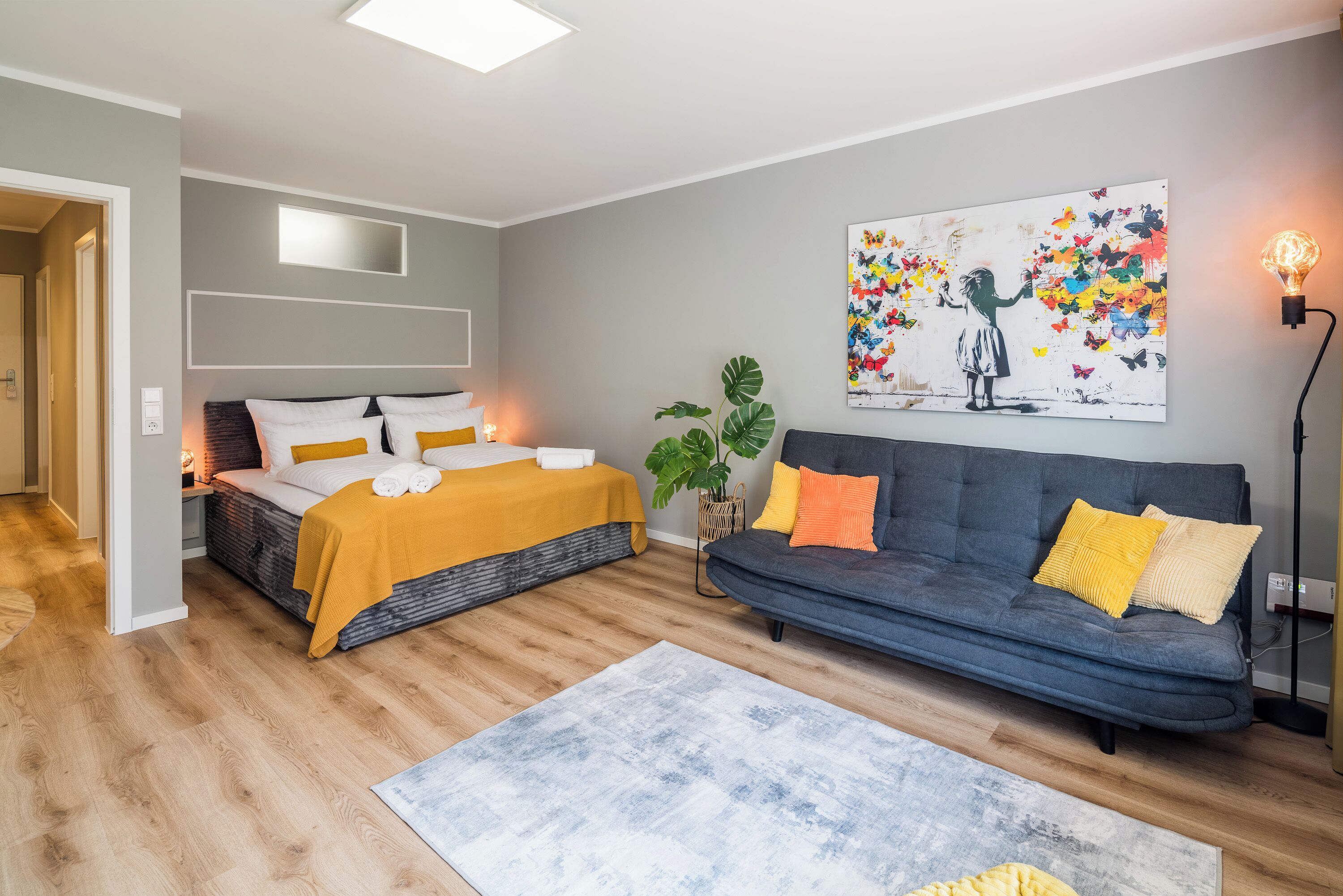 A modern bedroom with a bed, a sofa, and a painting on the wall.