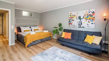 A modern bedroom with a bed, a sofa, and a painting on the wall.