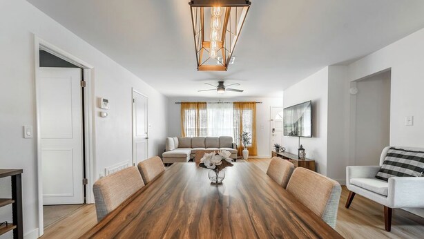 Ett rymligt matsalsrum med ett träbord, beige stoppade stolar och en modern hänglampa.