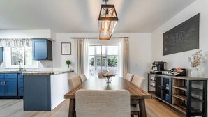 Ett modernt kök med matplats, med ett träbord, blå skåp och en hängande lampa.