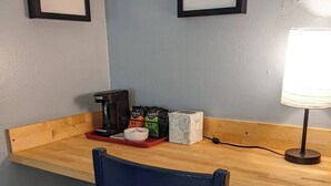 Un pequeño rincón de cocina con encimera de madera, cafetera, silla y lámpara de mesa.