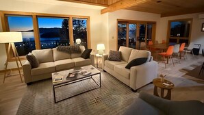 A modern living room with two sofas, a coffee table, and a dining area with chairs. - 3BR Chuckanut Drive home with sunset bay views, direct trail access, and hot tub (Bellingham)